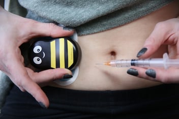 Woman uses Buzzy during an at-home IVF self-injection in stomach. 