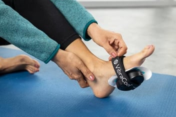 Woman using a VibraCool Plantar on bottom of her foot to relieve plantar fasciitis pain.
